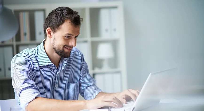 A professional working on a laptop in a bright office.